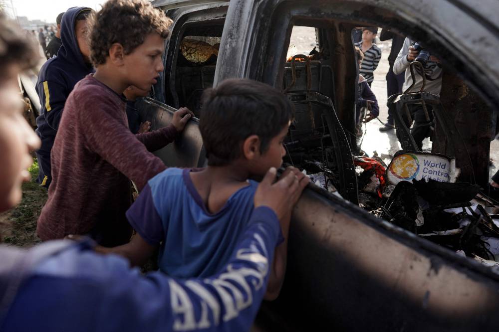 People gather around the carcass of a car used by US-based aid group World Central Kitchen, that was hit by an Israeli strike the previous day in Deir al-Balah in the central Gaza Strip on April 2, 2024. - Photo by AFP