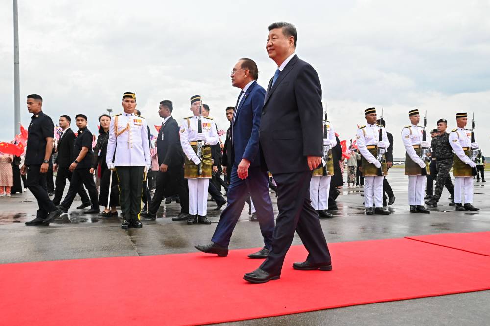 This handout photo taken and released by Malaysia's Department of Information on April 15, 2025 shows Malaysia's Prime Minister Anwar Ibrahim (centre, L) receiving China's President Xi Jinping (centre, R) upon his arrival at the Bunga Raya VIP complex of Kuala Lumpur International Airport in Sepang. (Photo by Farhan ABDULLAH / MALAYSIA'S DEPARTMENT OF INFORMATION/AFP)