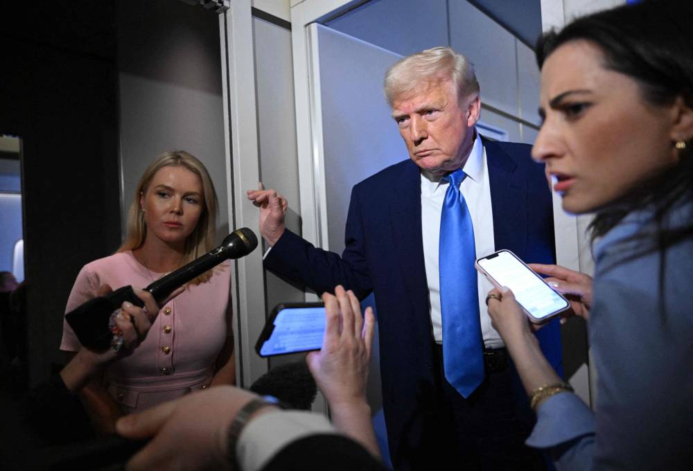 White House Press Secretary Karoline Leavitt listens (L) as US President Donald Trump speaks to reporters while in flight on Air Force One, en route to Joint Base Andrews on April 6, 2025. - (Photo by MANDEL NGAN / AFP)