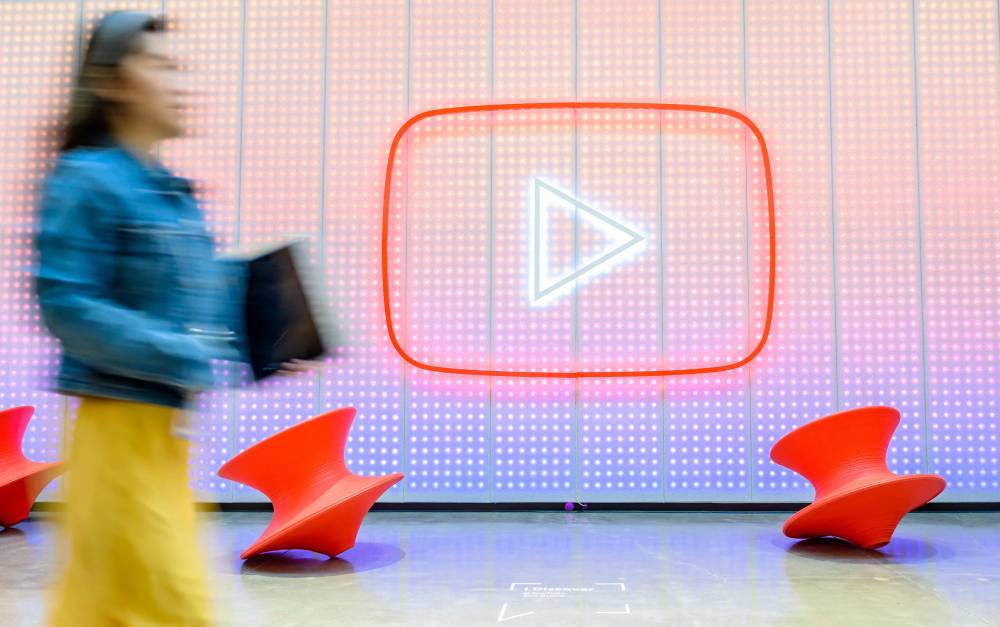 People walk by a YouTube logo, as Google celebrates the 20th anniversary of first video uploaded to YouTube, at the company's corporate headquarters in San Bruno, California, on April 23, 2025. (Photo by JOSH EDELSON / AFP)