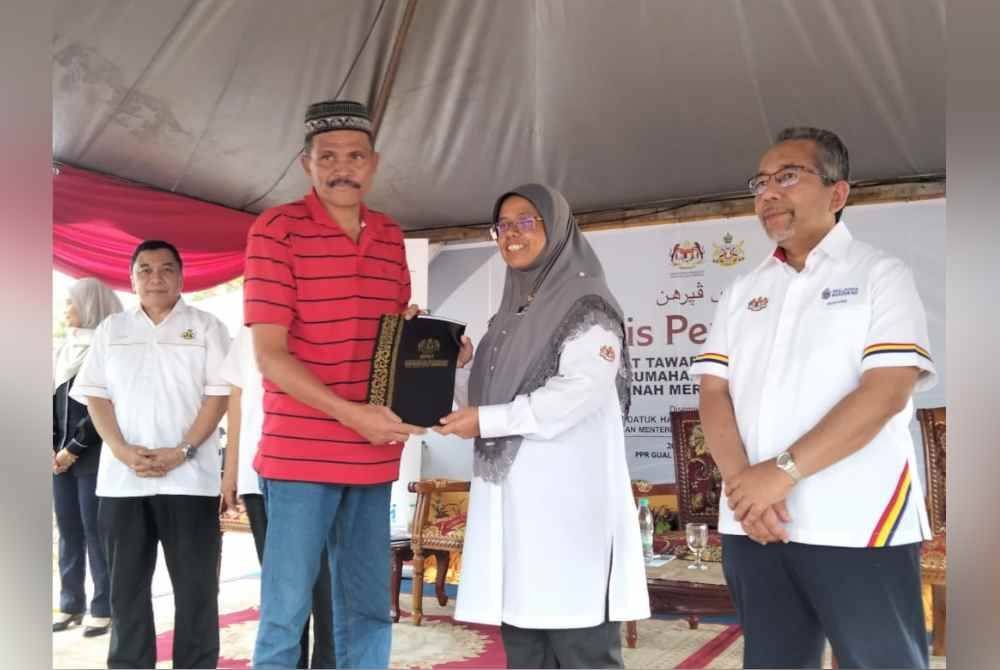 Aiman Athirah (dua, kanan) menyerahkan surat tawaran kepada penerima kediaman Program Perumahan Rakyat (PPR).